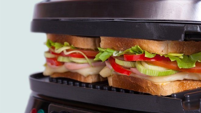 two ham, cheese and salad sandwiches toasting on a sandwich press